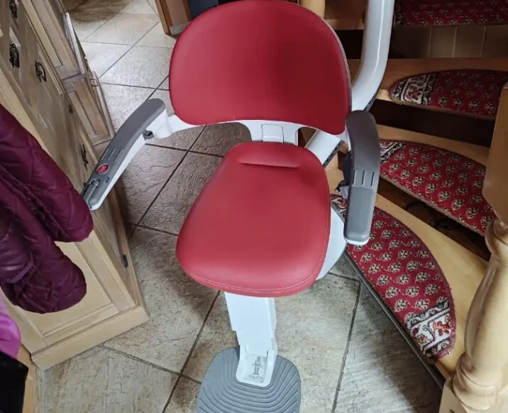 Treppenlift mit rotem Sitz auf gefliester Treppe