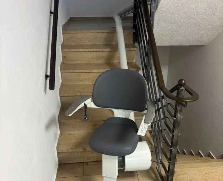 Treppenlift mit dunkelgrauem Sitz auf Steintreppe